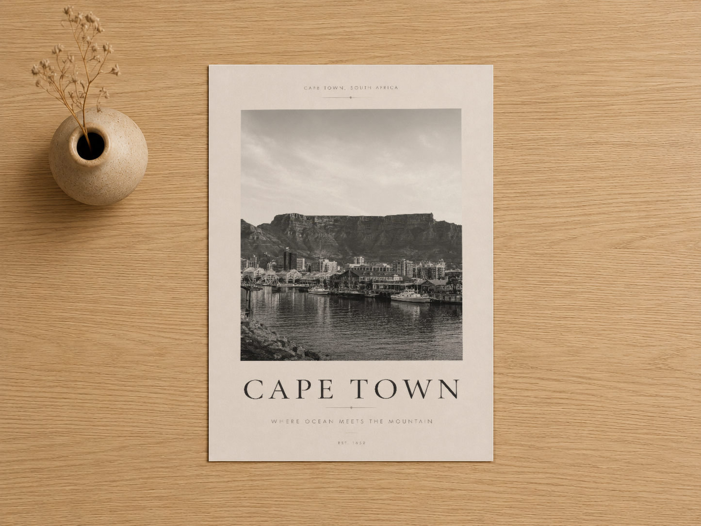 Cape Town deniz manzarası tablosu, hafif çerçeve içinde, ahşap zemin üstünde sanatsal kurguyla.