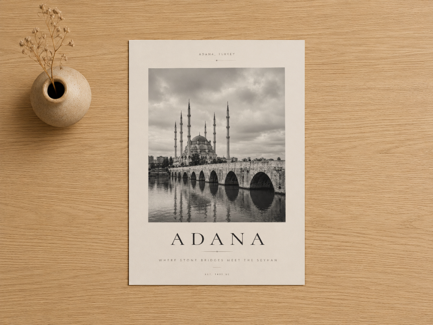 Adana'nın ikonik köprüsü ve camii motifli siyah-beyaz sanat baskısı, açık ahşap zemin üzerinde sergileniyor.