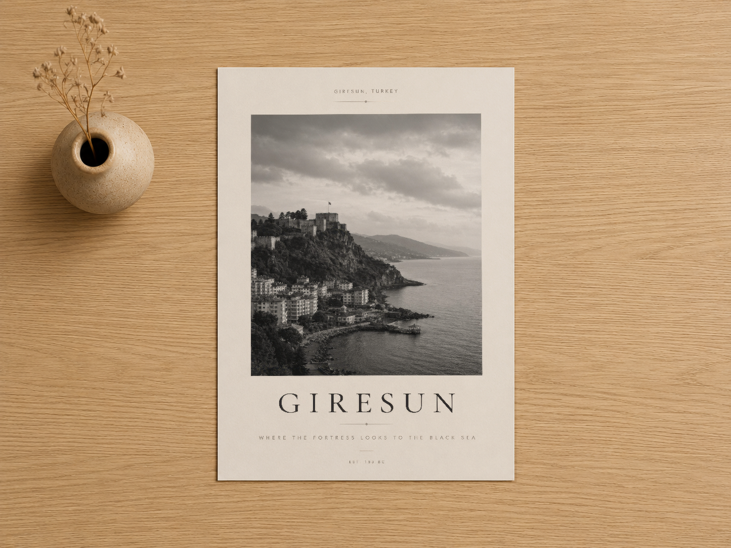 Giresun poster, ahşap masada seramik vazo ve kuru çiçek dekorasyonu yanında sergilenen siyah beyaz sahil fotoğrafı.