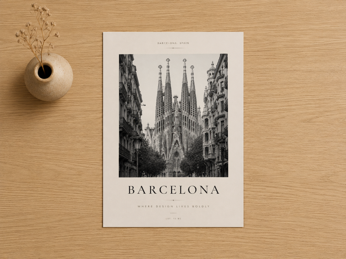 Sagrada Familia'nın ikonik mimarisini siyah beyaz fotoğrafla sunan sanat baskısı, kream tonlu çiçek vazosuyla ahşap zeminde.