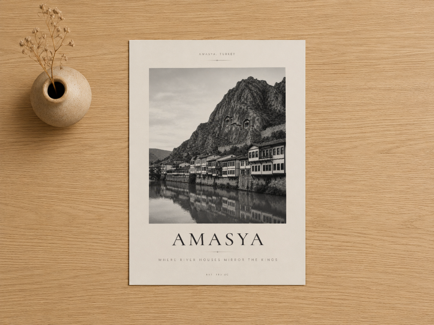 Dağ eteklerindeki tarihi evleri ve nehir yansımasını gösteren Amasya travel art print, minimalist beyaz mat ve siyah yazı