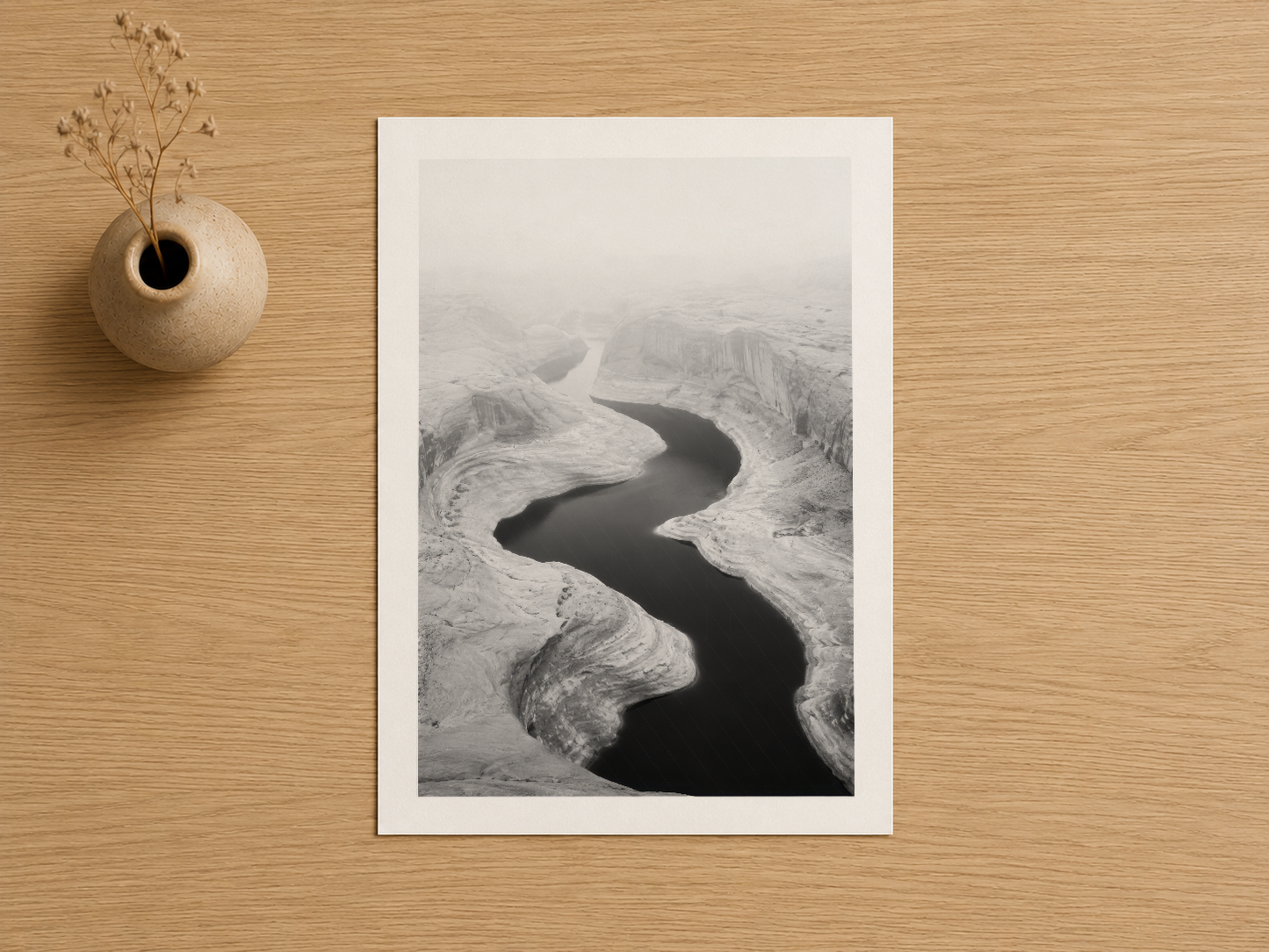 Aerial nehir manzarası, minimalist beyaz mat poster, doğal ahşap yüzeyde sergilenen siyah beyaz fotoğraf.