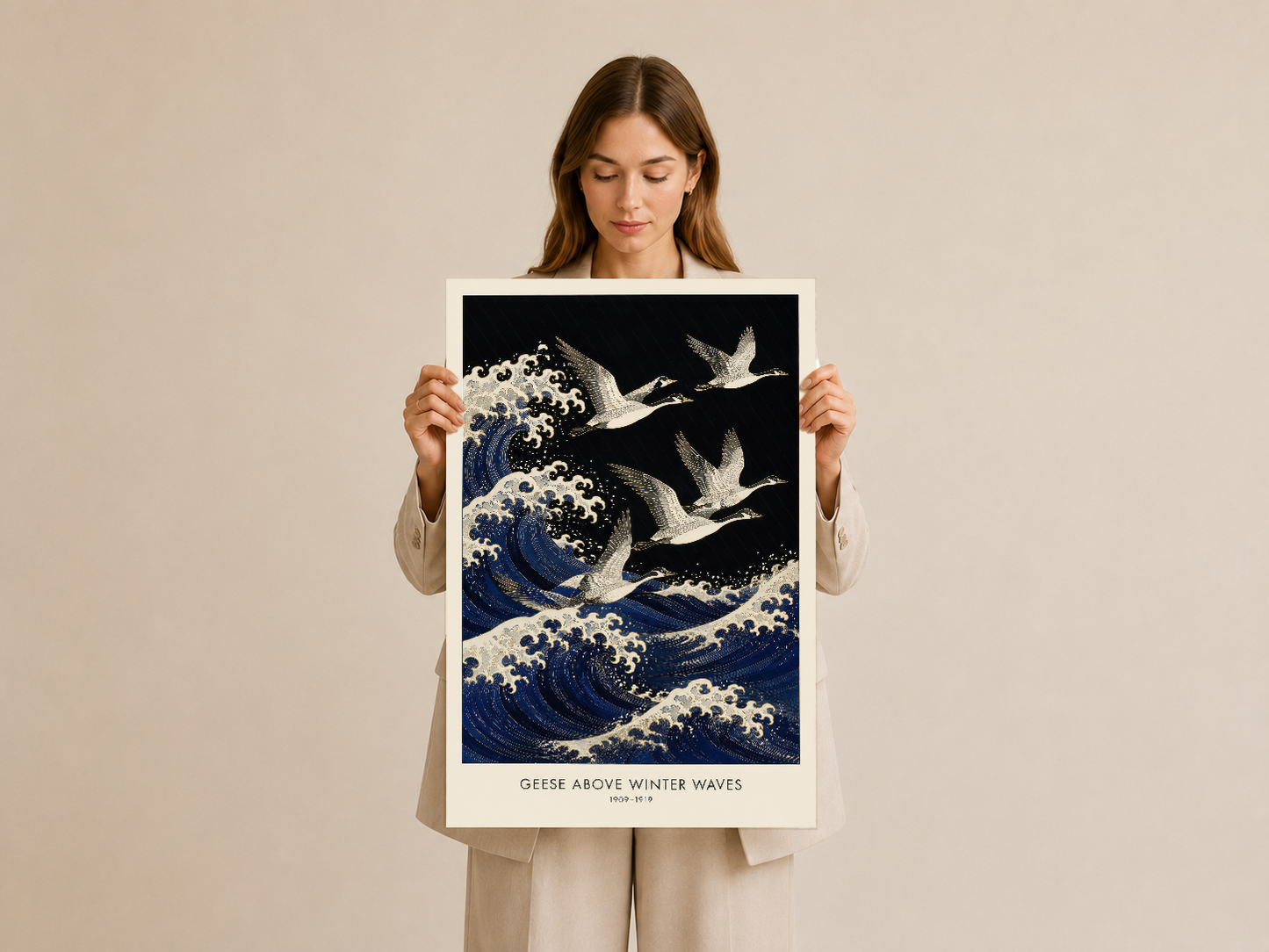 Kadının tuttuğu Geese Above Winter Waves tablosu, işlemeli dalgalar ve kuş motifleriyle estetik bir dekorasyon parçası.