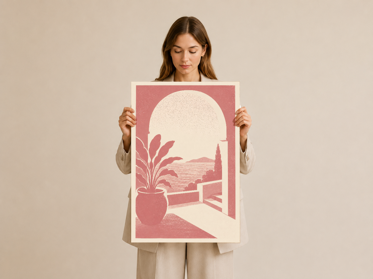 Kadın elinde tutulan, pamuk beyazı çerçeveli poster sıcak pembe renkleriyle balkondan deniz manzarasını betimler.