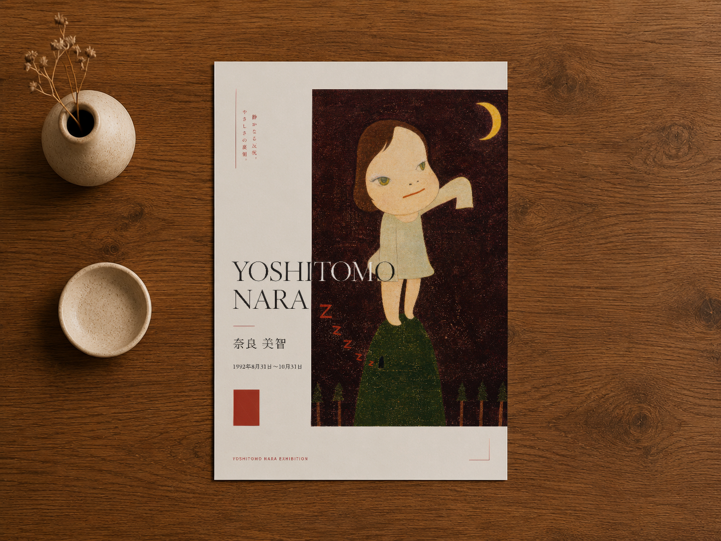 Yoshitomo Nara posteri, ahşap yüzeyde seramik tasarımcı objeler ile stillendirilmiş, yukarıdan fotoğraflanmış.