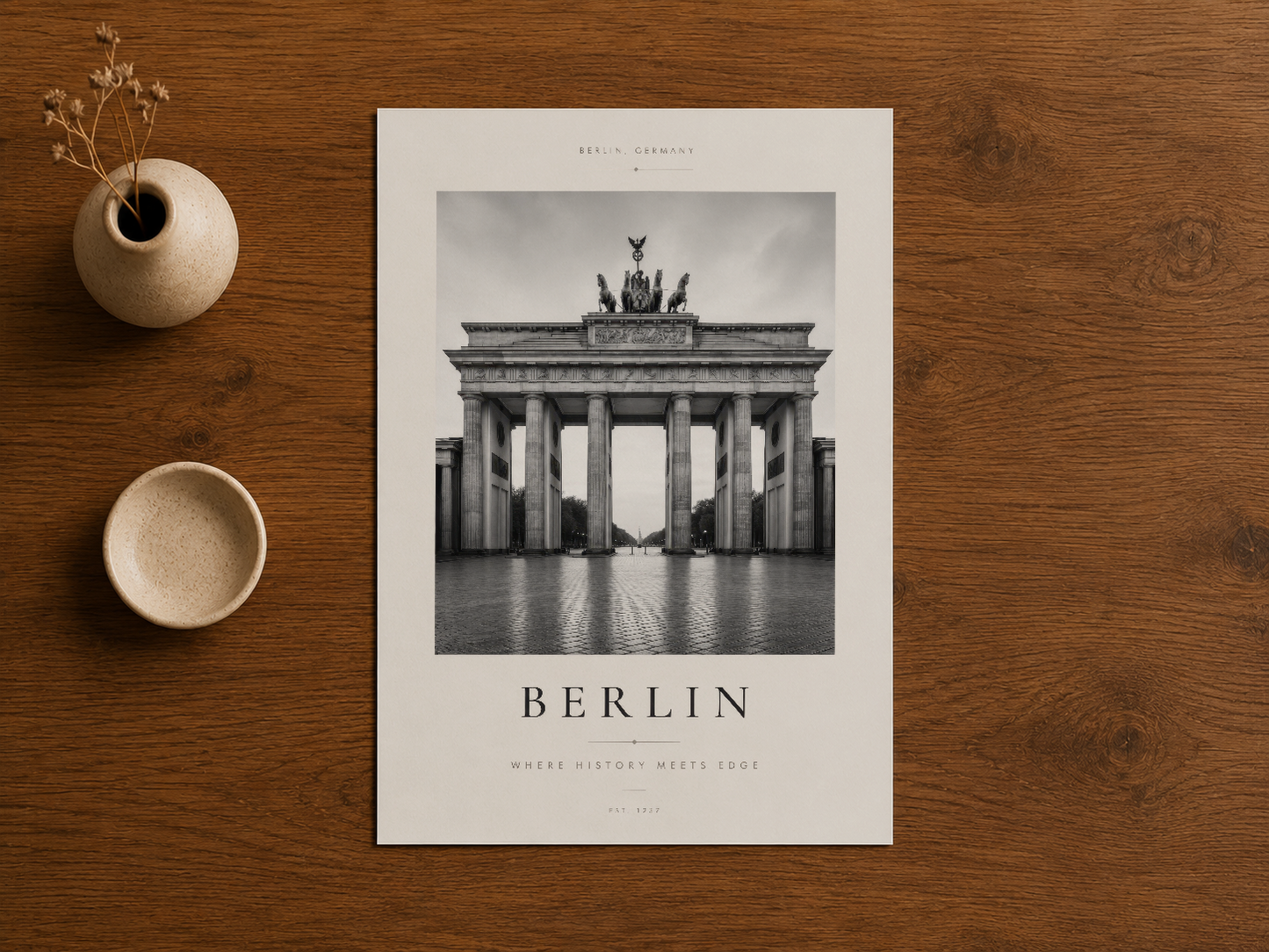 Brandenburg Kapısı'nın etkileyici siyah beyaz fotoğrafını içeren Berlin poster, ahşap zemin üstünde stillendirme görseli.