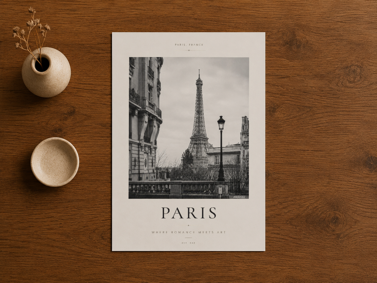 Paris posterinin ahşap masa üzerinde, dekoratif seramik eşyalarla birlikte stillenen fotoğraf baskısı.