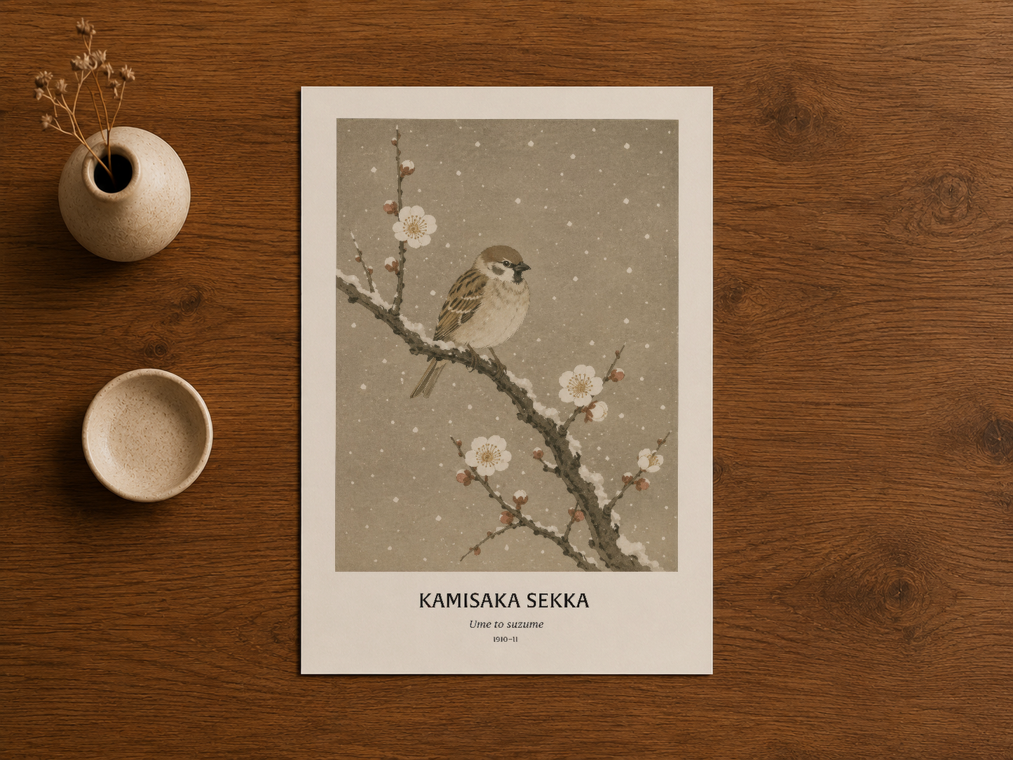 Kamisaka Sekka tablosu, beige ve gri tonlarında çiçek dalında konuşan kuş resmi, ahşap masa üstünde sergilenen poster.
