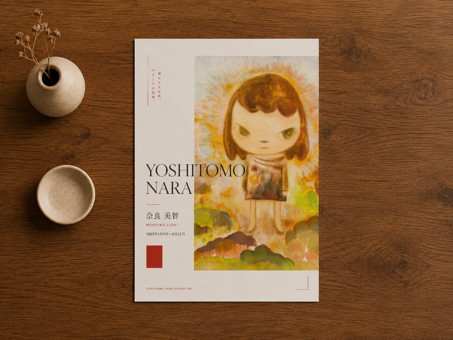Doğal ahşap masa üzerinde düzenlenmiş Yoshitomo Nara sanat baskısı ve dekoratif aksesuarlar.