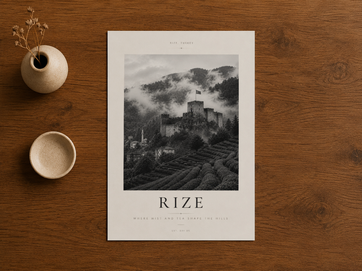 Rize kalesinin dramatik siyah-beyaz fotoğrafyası, beyaz poster çerçevesinde, doğal ahşap zemin üzerinde sakin şekilde
