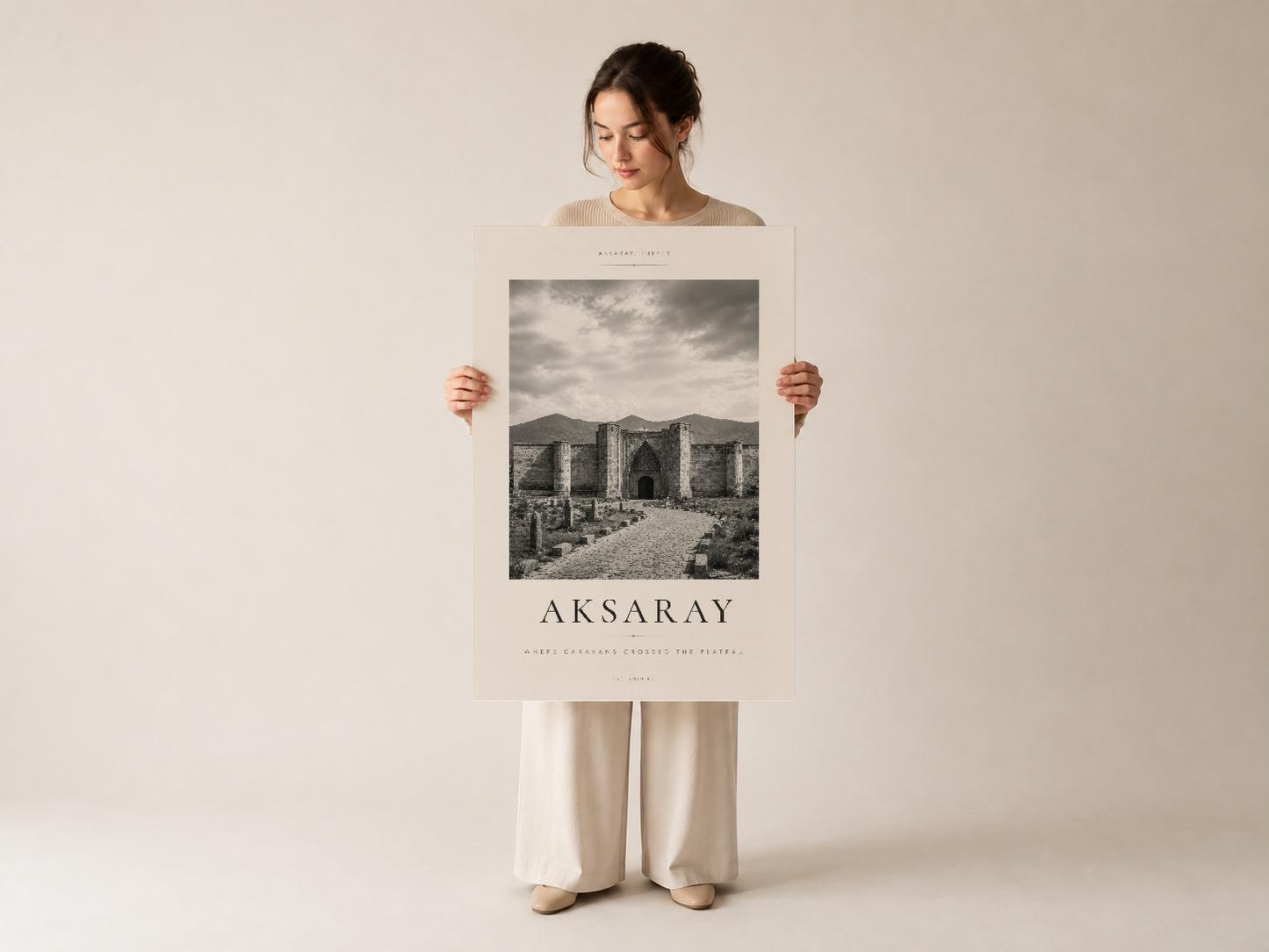 Aksaray duvar tablosu, kadın tarafından sergilenen beyaz baskılı poster, tarihi yapının dramatik siyah beyaz görüntüsü.