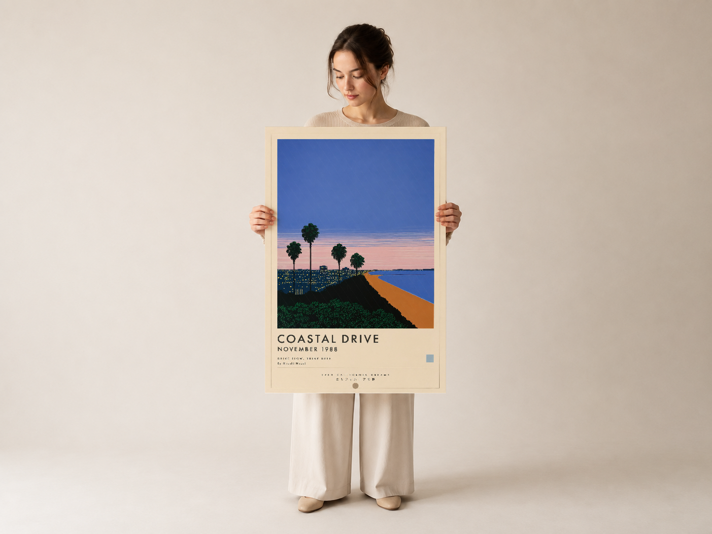 Coastal Drive kıyı yolu tablosunu tutan kadın, sade tasarımlı retro desen baskısı poster gösteriyor.