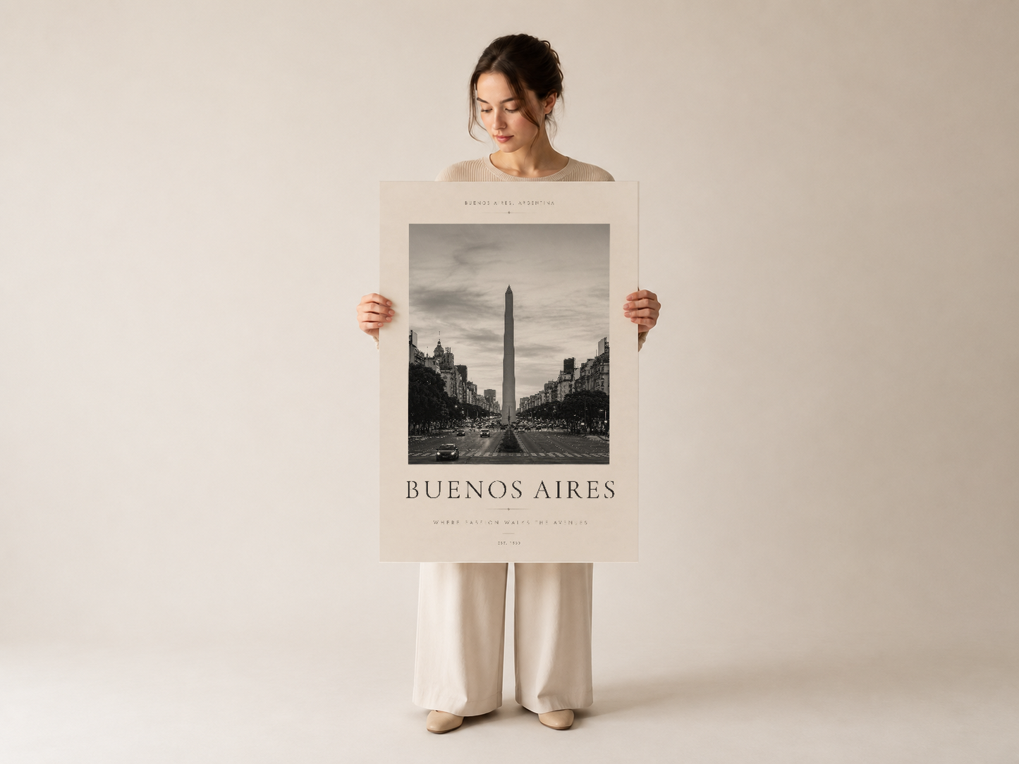 Nötr giysileriyle poz veren kadının tuttuğu Buenos Aires Obeli posterinin klasik tipografi ve mimari fotoğrafı.