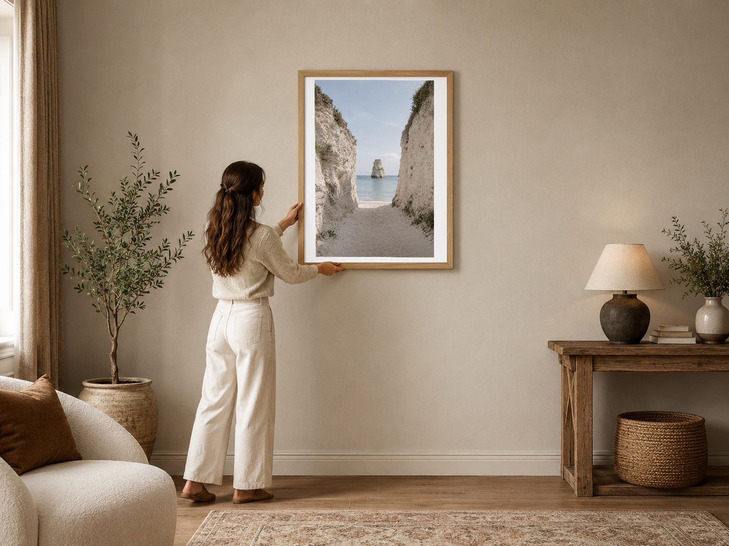 Beyaz çerçeveli deniz manzarası tablosu, iki kaya arasından turkuaz denizi ve kumsalı gösteren sakin ve minimalist sahne.