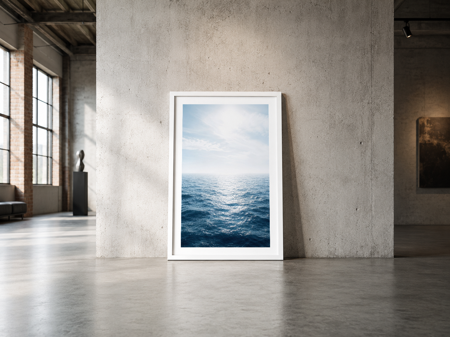 Işıl işıl deniz dalgalarını gösteren çerçeveli poster, endüstriyel betonlu açık alanda sergileniyor.