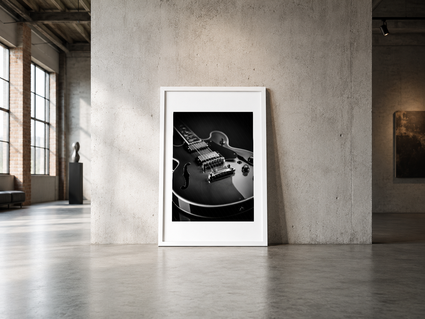 Siyah ve beyaz gitar sanat tablosu, beyaz çerçeveliyle endüstriyel galeride sergileniyor.