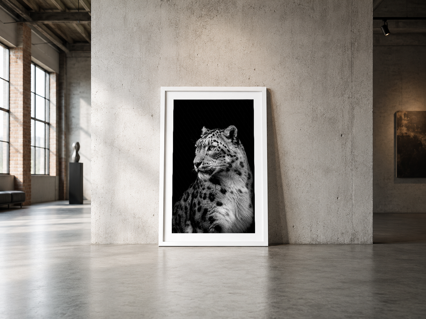 Endüstriyel tarzda beyaz çerçeveli, siyah beyaz kar leoparı tablosu beton duvarda.