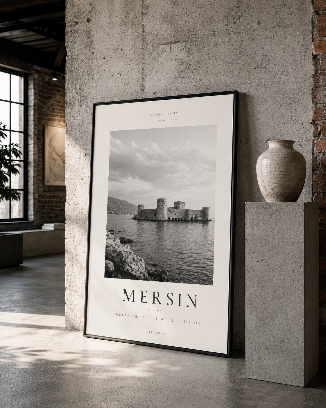 Mersin deniz manzarası tablosunun siyah çerçevesiyle endüstriyel loft stilinde, tuğla ve çimento duvarlar arasında sunulması.