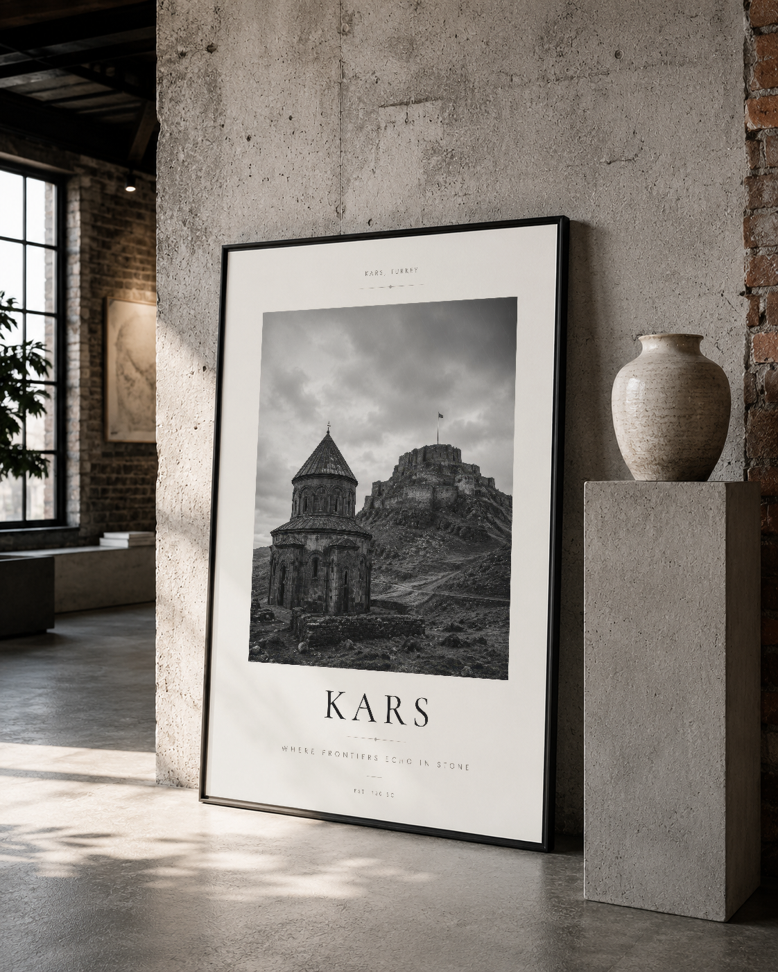 Siyah çerçeveli Kars kilise posteri, raw betonlu loft stüdyoda rafta asılı, minimalist tasarım.