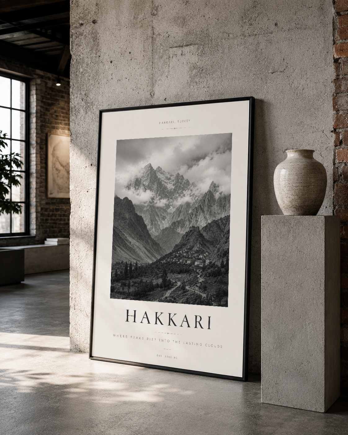 Siyah çerçeveli Hakkari posteri, tuğla ve betona çevrili galeri ortamında, minimalist dekorasyonla birlikte gösteriliyor.