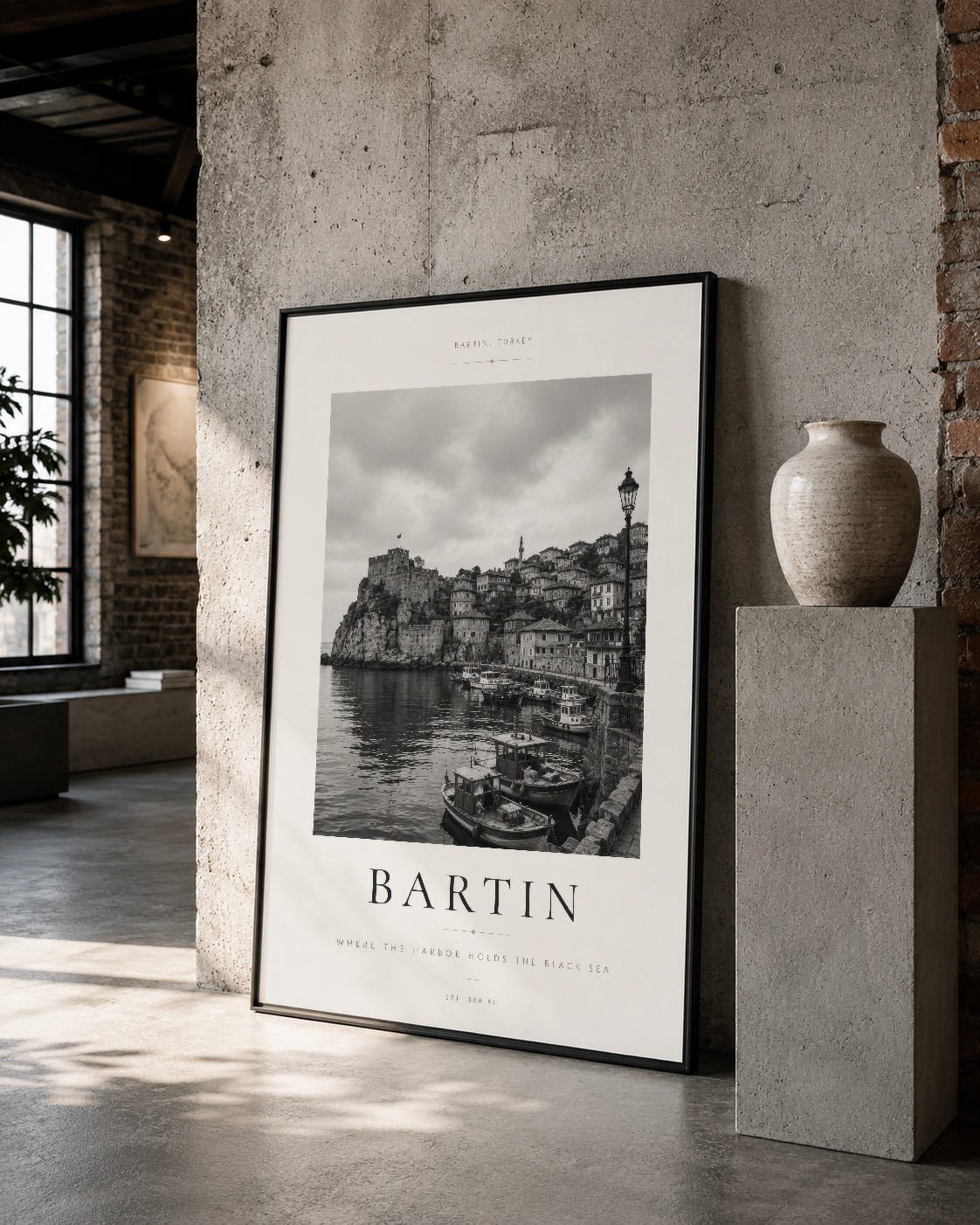 Bartın deniz ve mimari detayları siyah çerçeveli poster, depo tarzı mekanda rustik seramik vazo ile beraber.