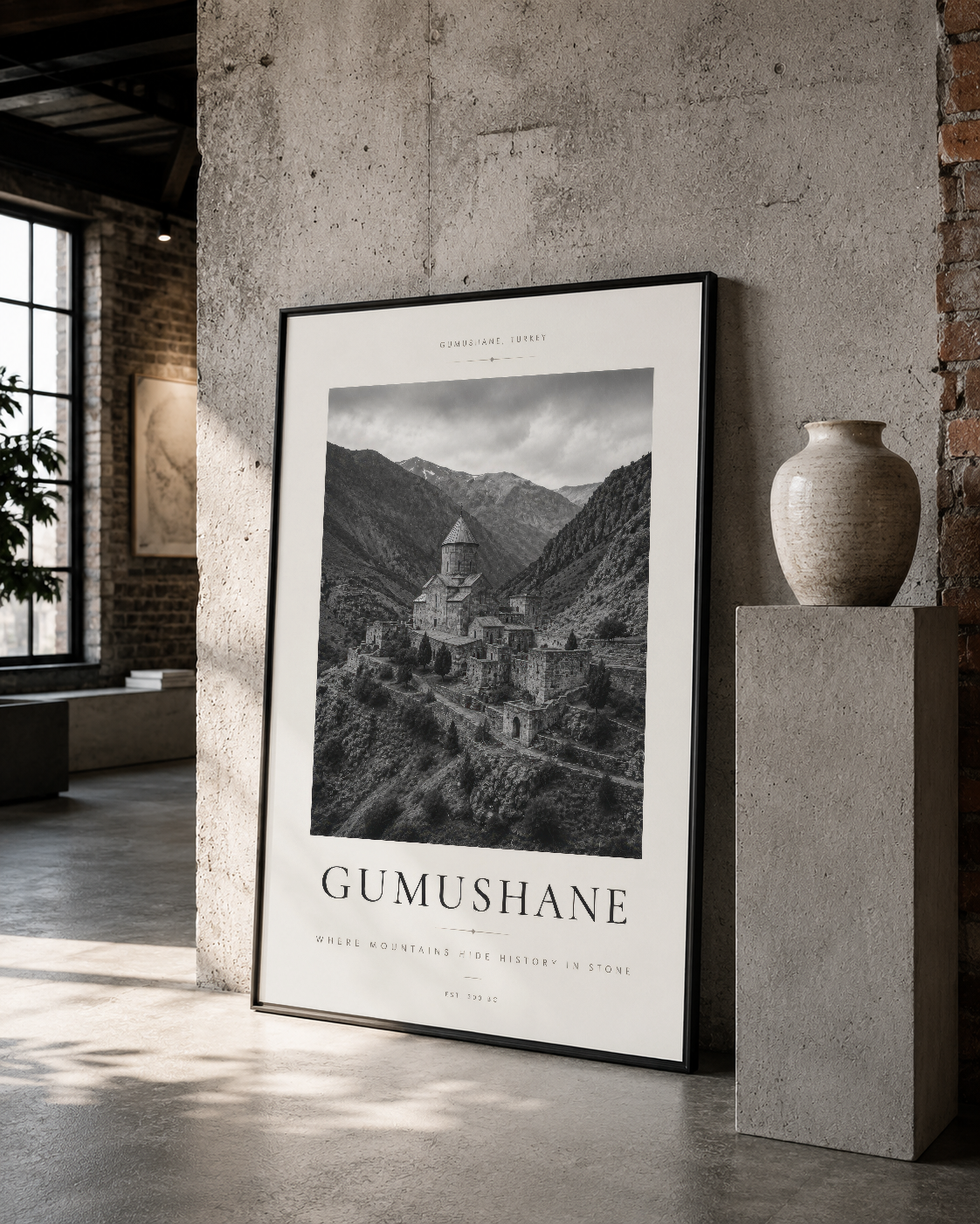 Gümüşhane mimarisini siyah çerçeveli poster, betonlu galerı duvarında sanatsal sunum.