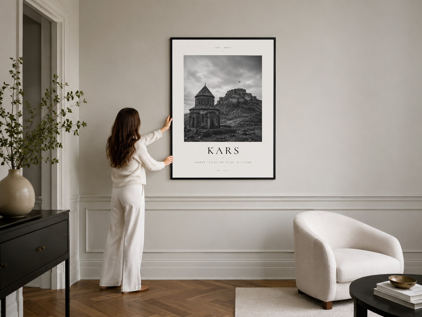 Kars kilisesi siyah çerçeveli sanat tablosu, şık modern yaşam odasında beyaz duvar paneli üzerinde asılı.