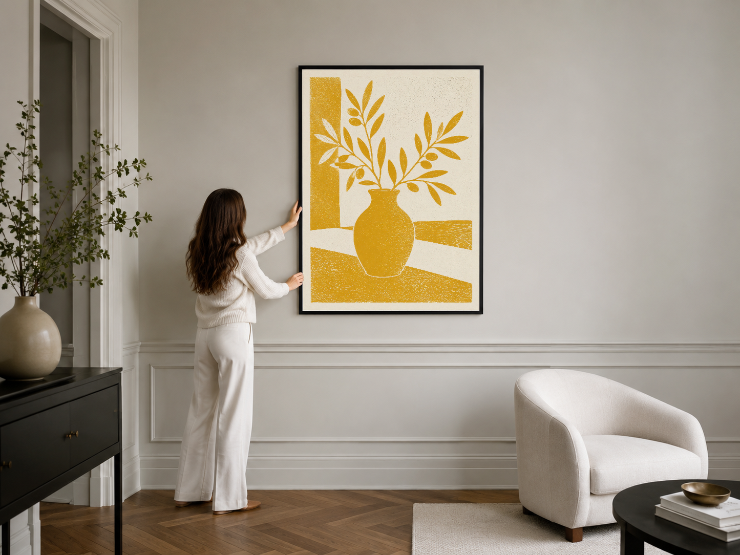 Canlı altın renkli vazo ve yaprak motifli duvar sanatı, siyah çerçevede minimalist iç mekanda.