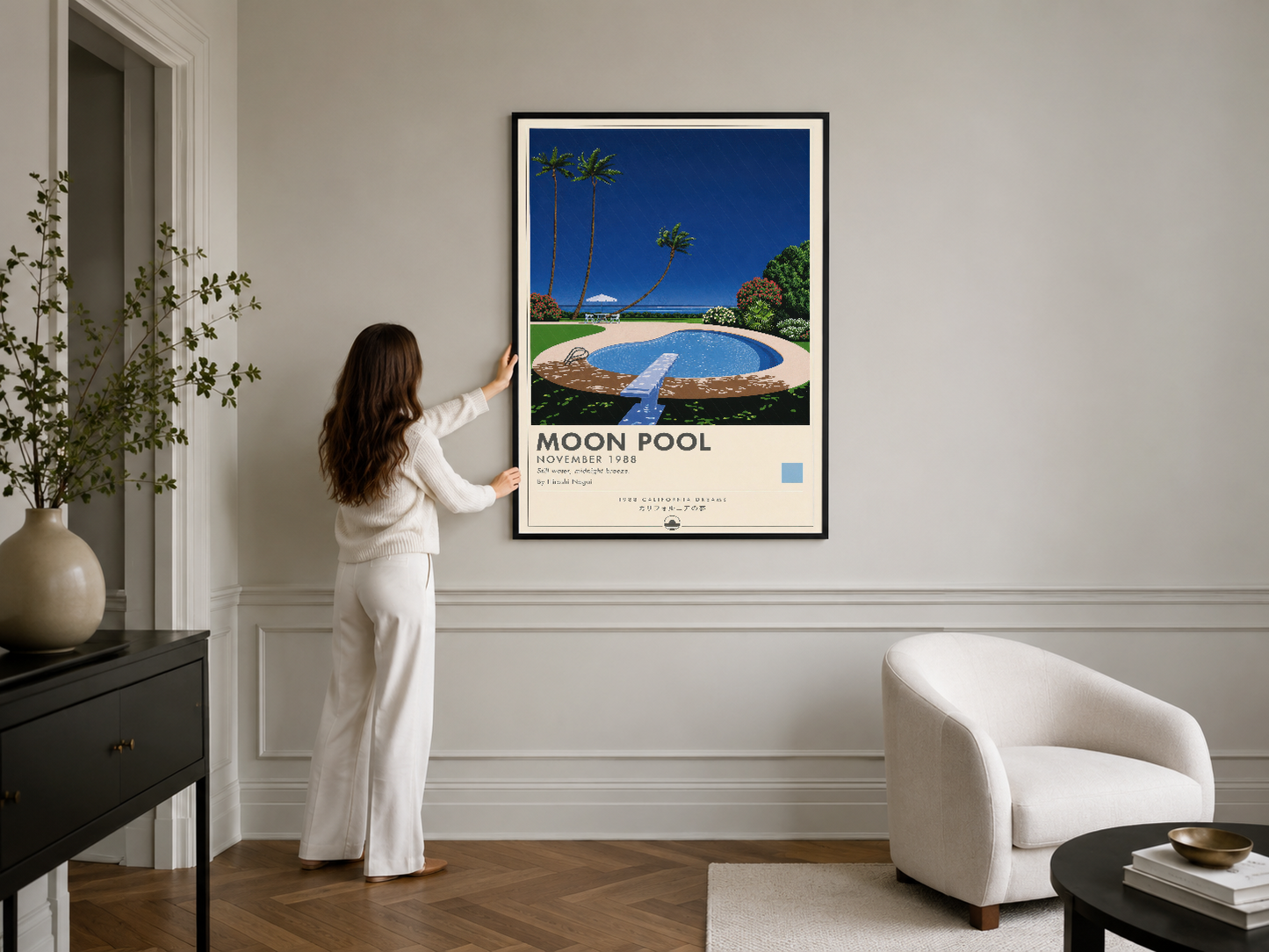 Siyah çerçeveli Moon Pool posteri, minimalist modern iç tasarımda beyaz koltuğun üstündeki duvar panelinde yer almaktadır.