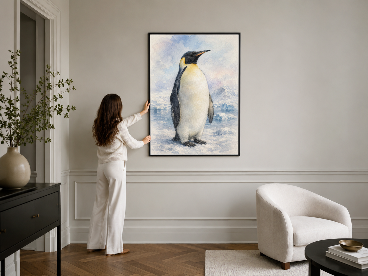 Siyah çerçeveli penguen sanat eseri, şık oturma odasında beyaz sessel yanında duvardan asılı modern dekor.