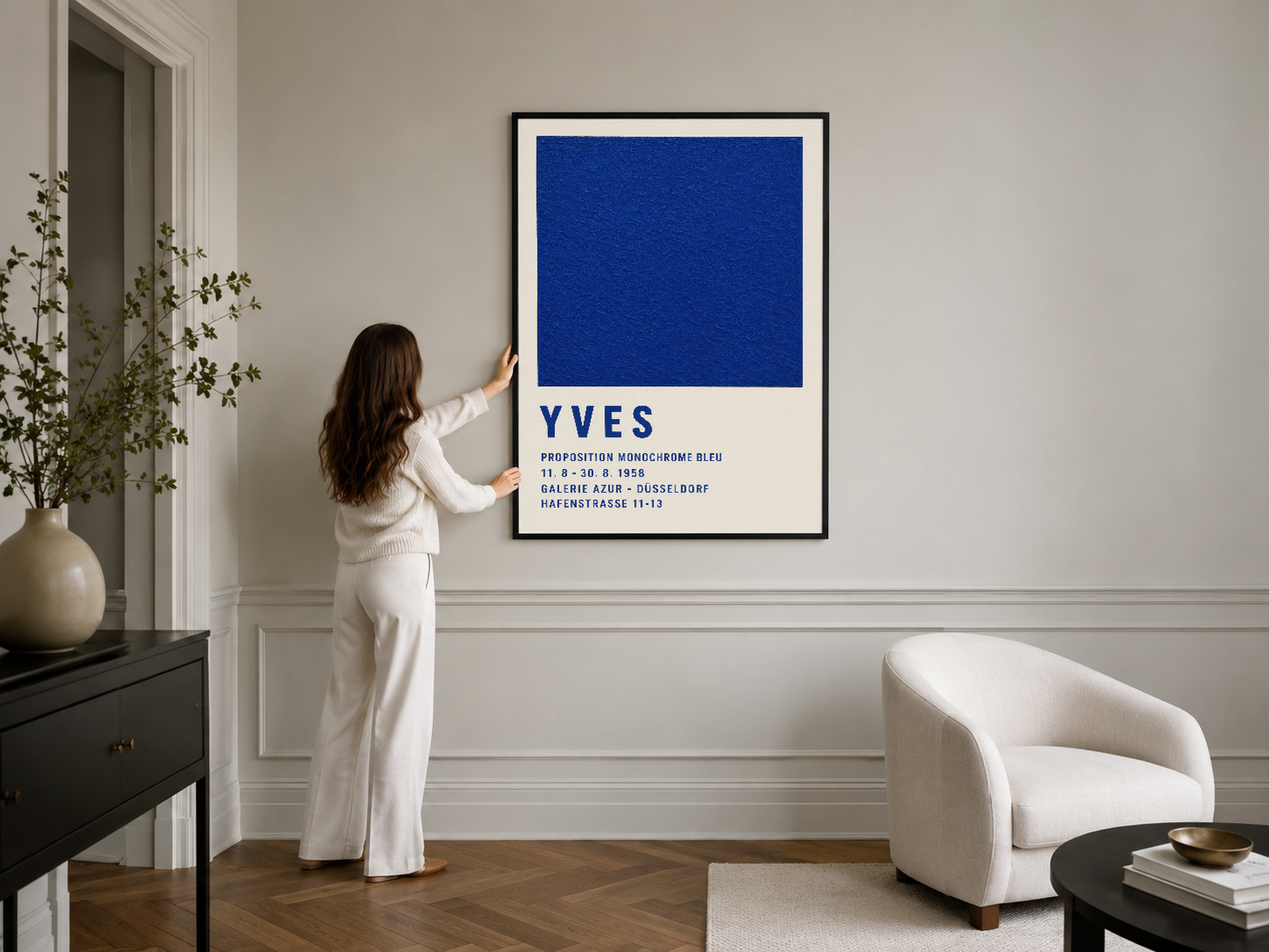 Modern oturma odasında siyah çerçeveli Yves tablosu, mavi geometrik form ve kurumsal metin detayları ile.
