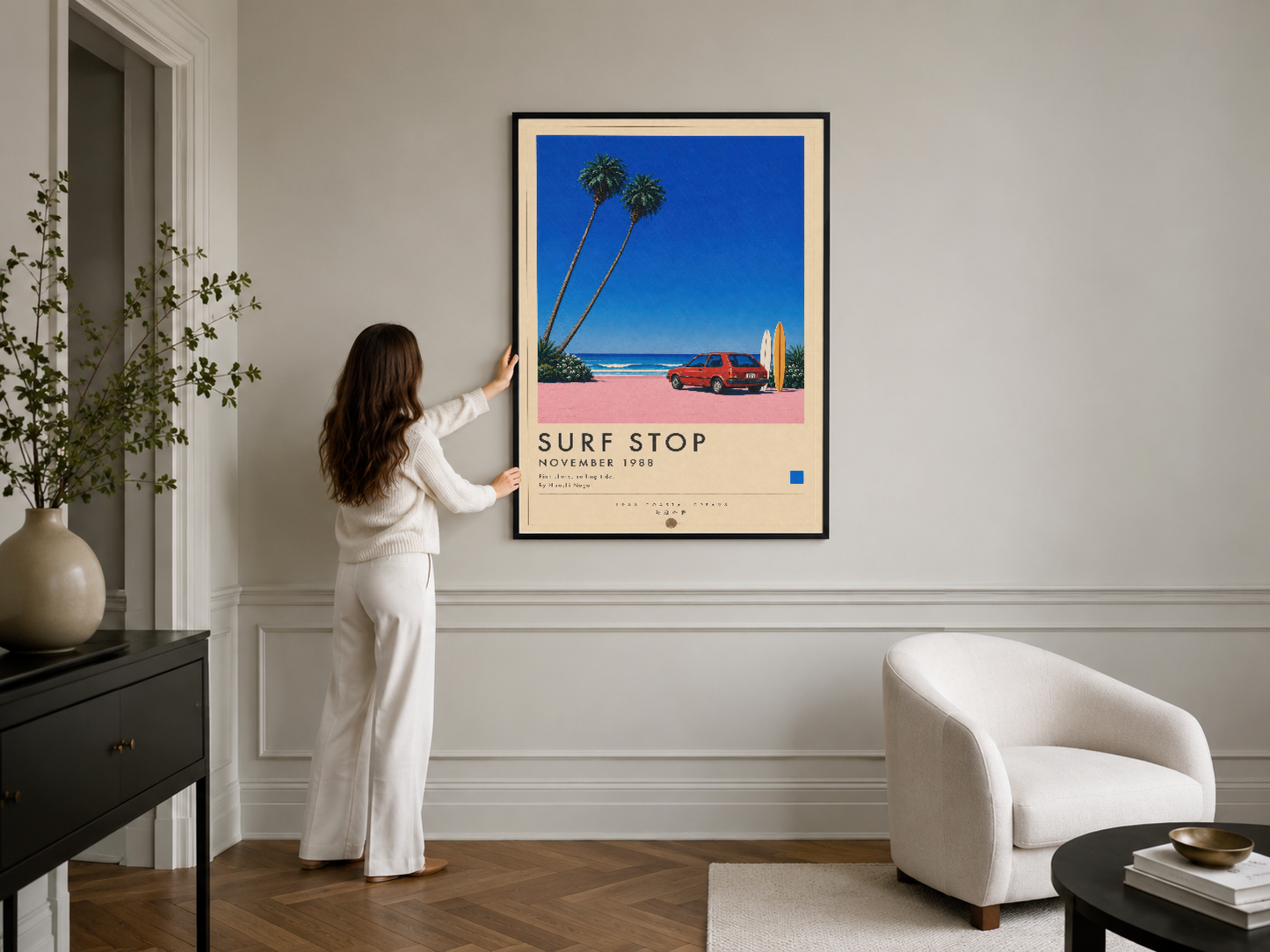 Sahil temalı modern poster, siyah çerçeveli, minimal iç tasarımda beyaz koltuk yanında asılı duran sanat tablosu.