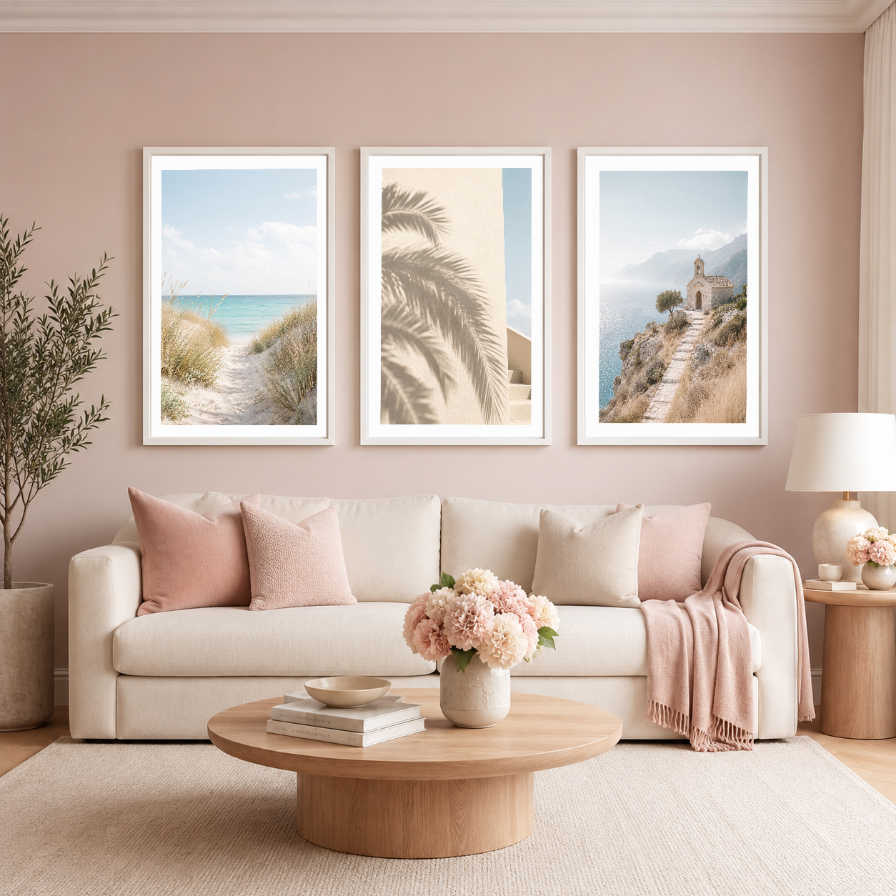 Beyaz çerçeveli üç panel tablo seti, pembe tonlu rahat oturma odasında plaj ve deniz tema sanat eserleri.