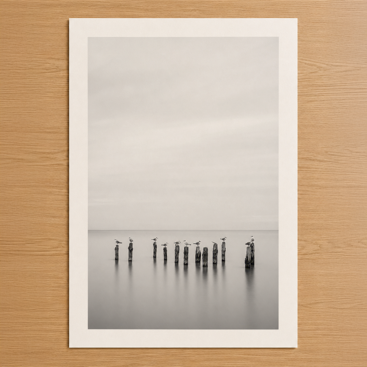 Minimalist siyah beyaz fotoğraf sanat baskı, sakin su üzerinde ahşap direkleri gösteren huzurlu doğa tablosu.