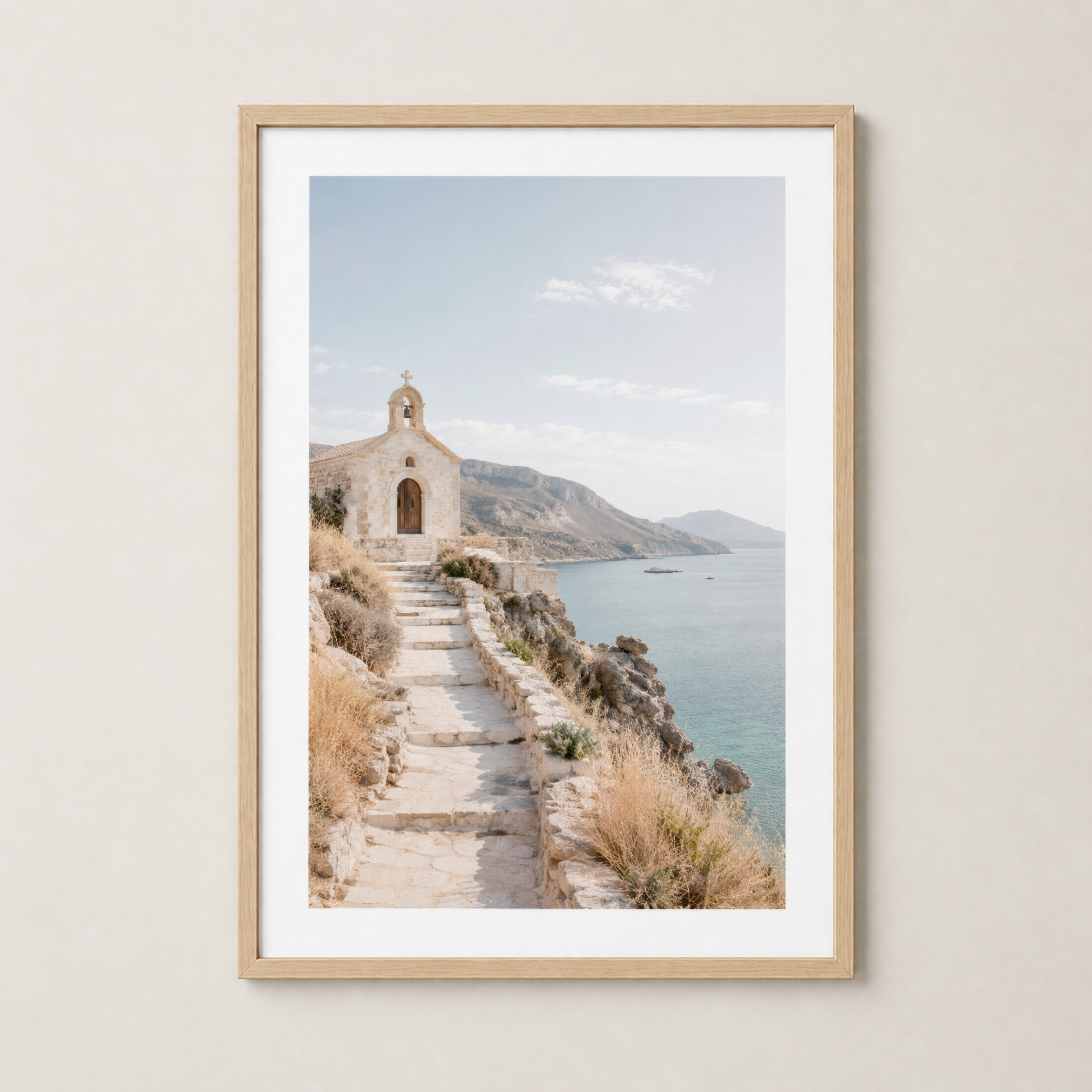 White chapel on hillside stairs above turquoise waters, wooden frame display