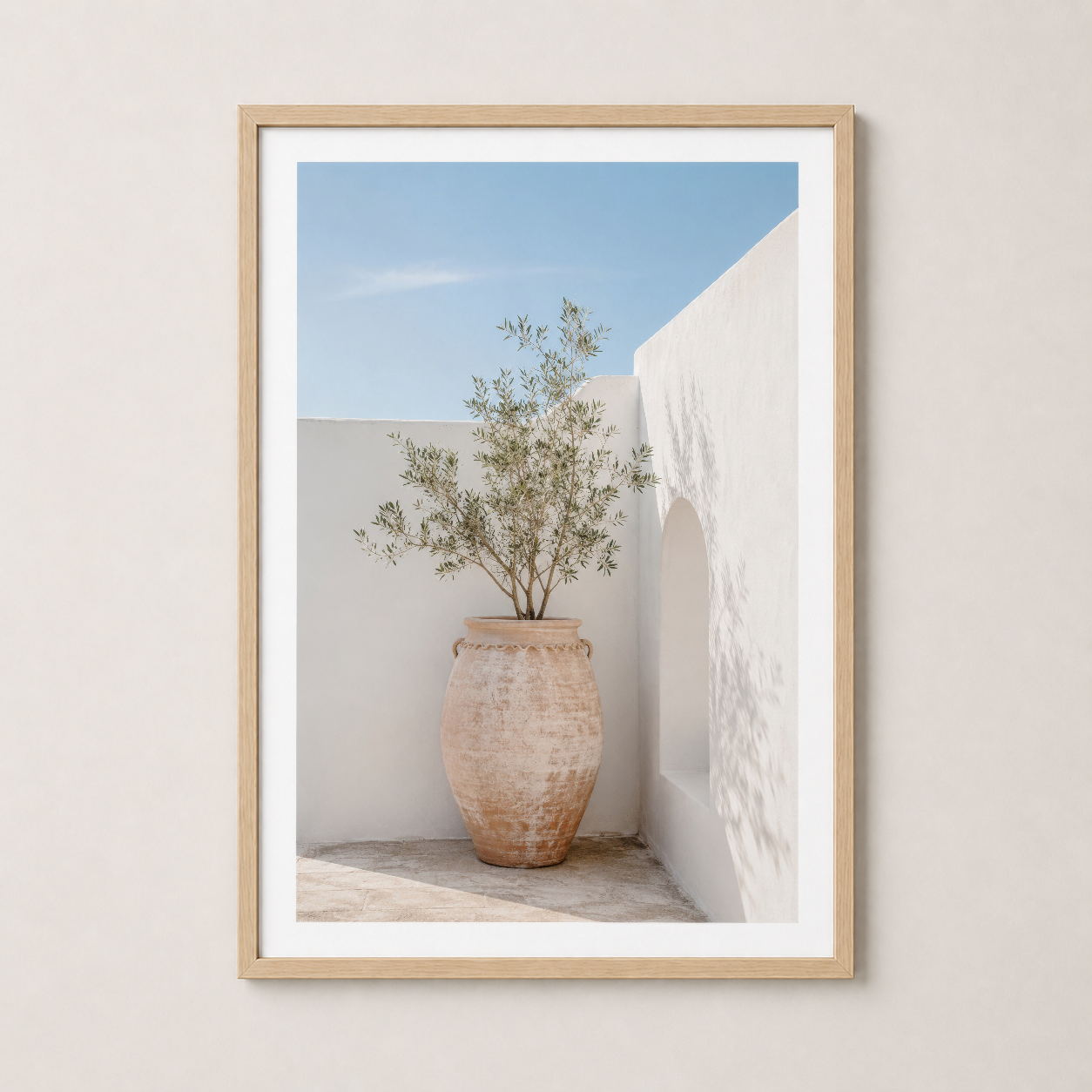 Doğal ahşap çerçeveli sanat eseri, minimalist beyaz mimarinin içinde vintage terrakotta saksıda bitki.