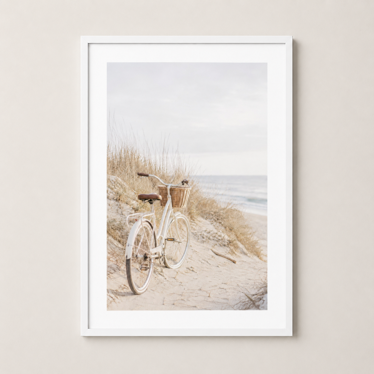 Beyaz çerçeveli poster, kum tepesindeki retro bisikletin atmosferik kıyı görünümü ve boho estetik.