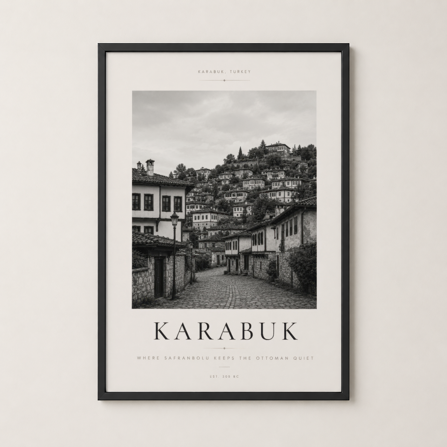 Karabük şehir manzarası siyah çerçeveli duvar tablosu, taş sokaklar ve tepedeki evleri kapsayan atmosferik siyah beyaz baskı.
