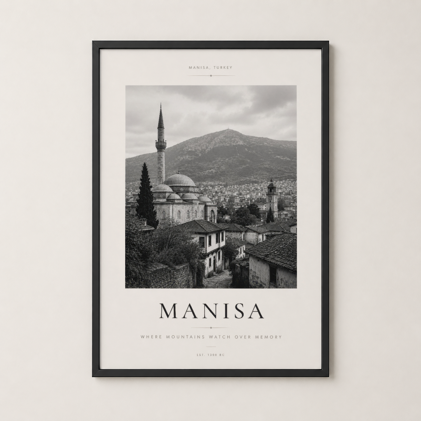 Manisa şehrinin nostaljik görünümünü siyah çerçevede sunan sanat baskısı, duvara asılı.