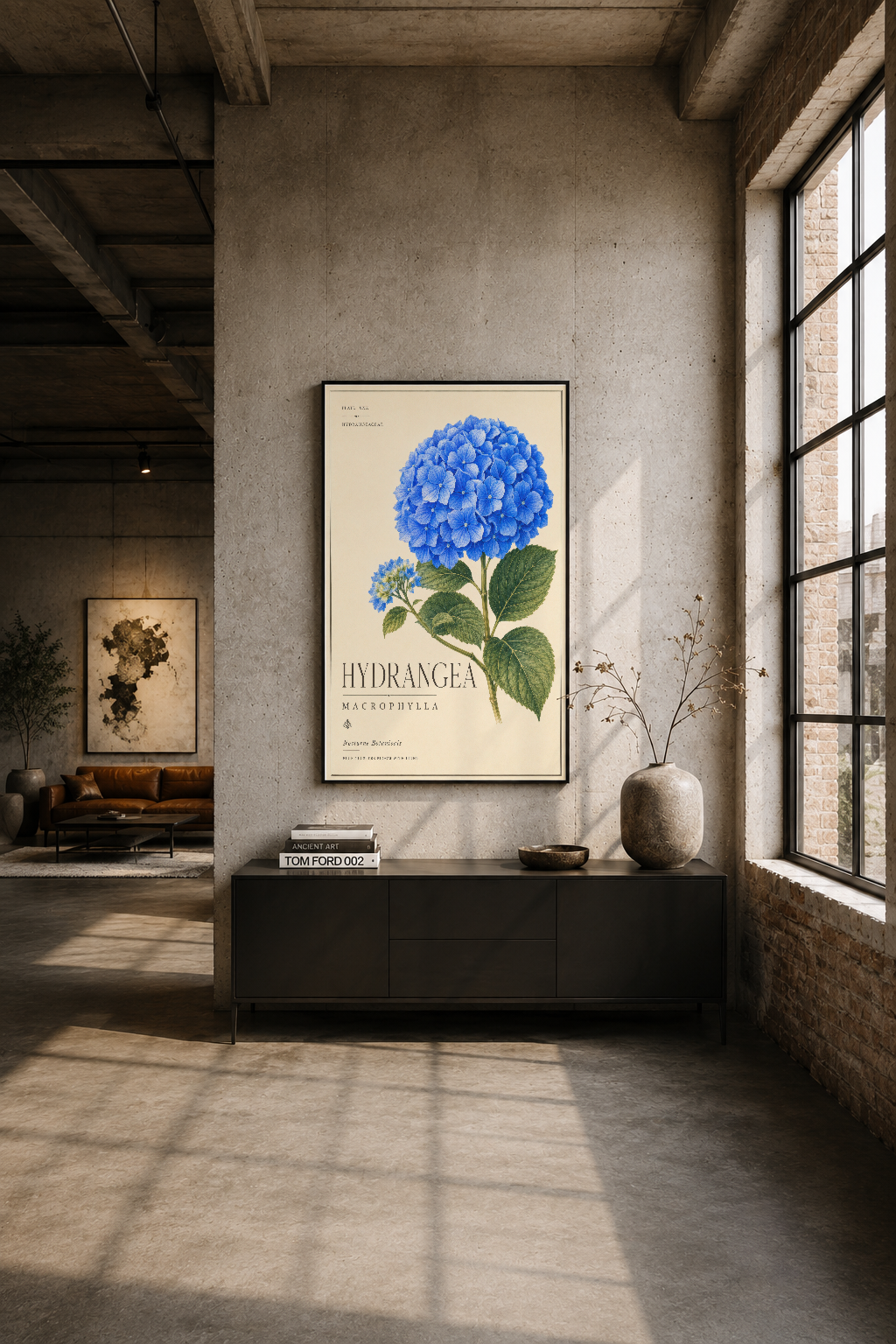 Modern endüstriyel oturma alanında siyah çerçeveli hortensia duvar tablosu, betonlu duvarın başında sergileniyor.