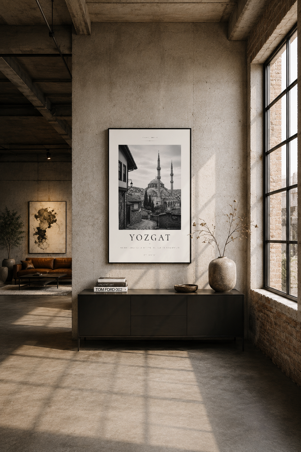 Çağdaş loft oturma alanında siyah çerçeveli Yozgat tablosu, betonun karşısında sade ve etkileyici sanat dekorasyonu olarak