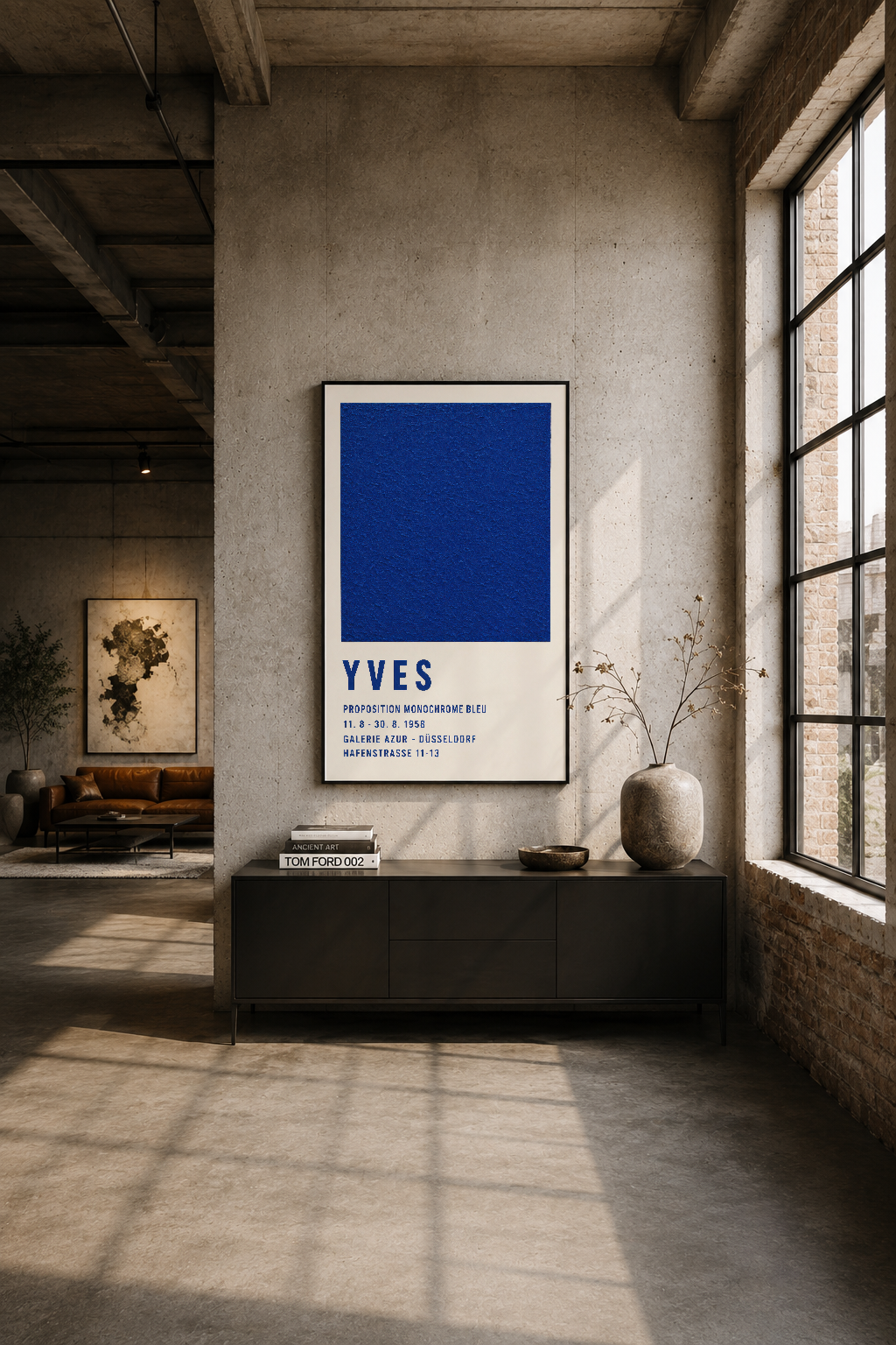 İndüstriyel loft tarzı betonlu duvarı süsleyen siyah çerçeveli Yves Klein tablosu, güneş ışığında dramatik atmosfer yaratır.