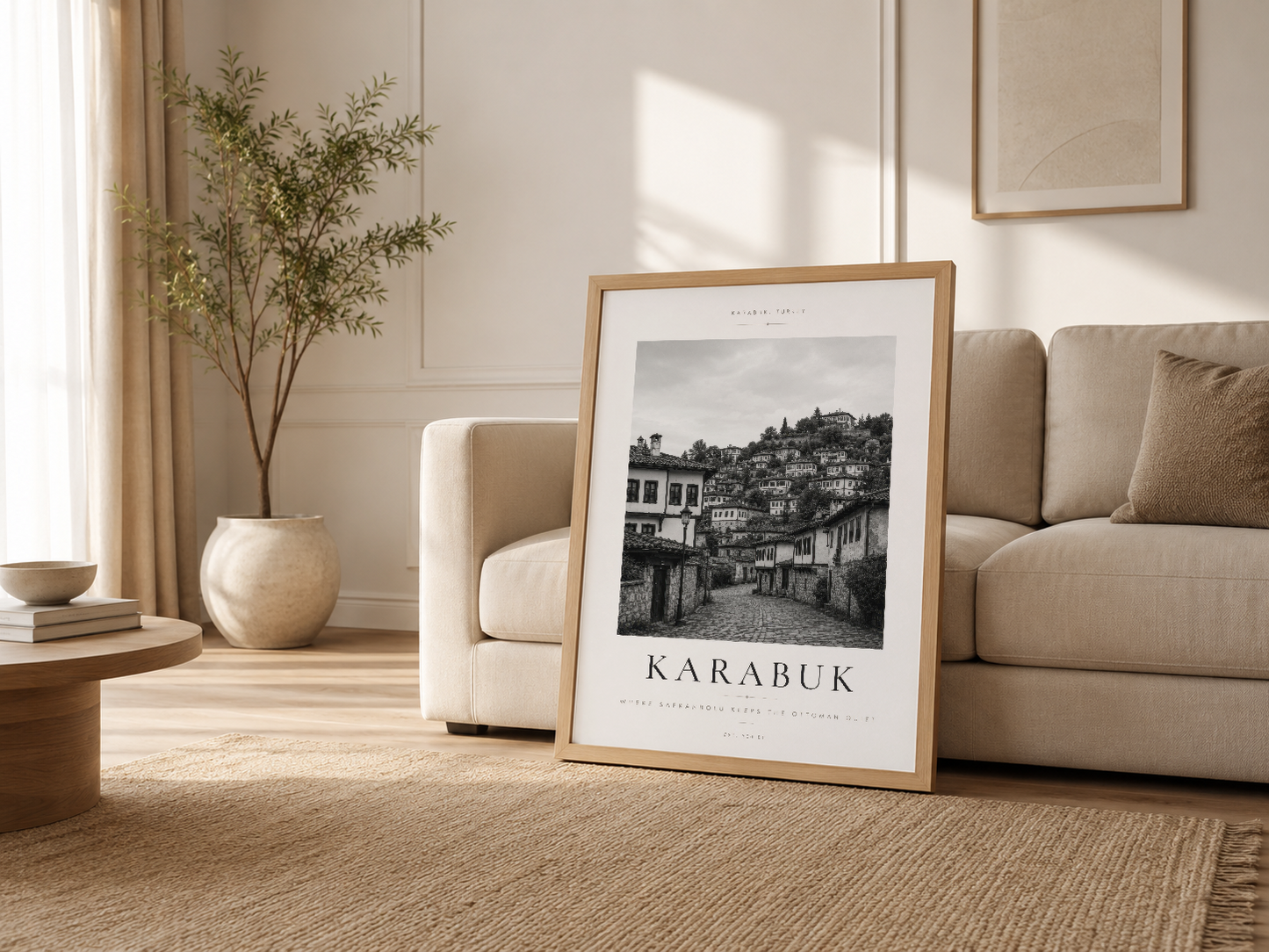 Krem sofa yanında ahşap çerçeveli Karabük tablosu, ışığın içinden geçtiği minimalist oturma alanında sanat dekorasyon.