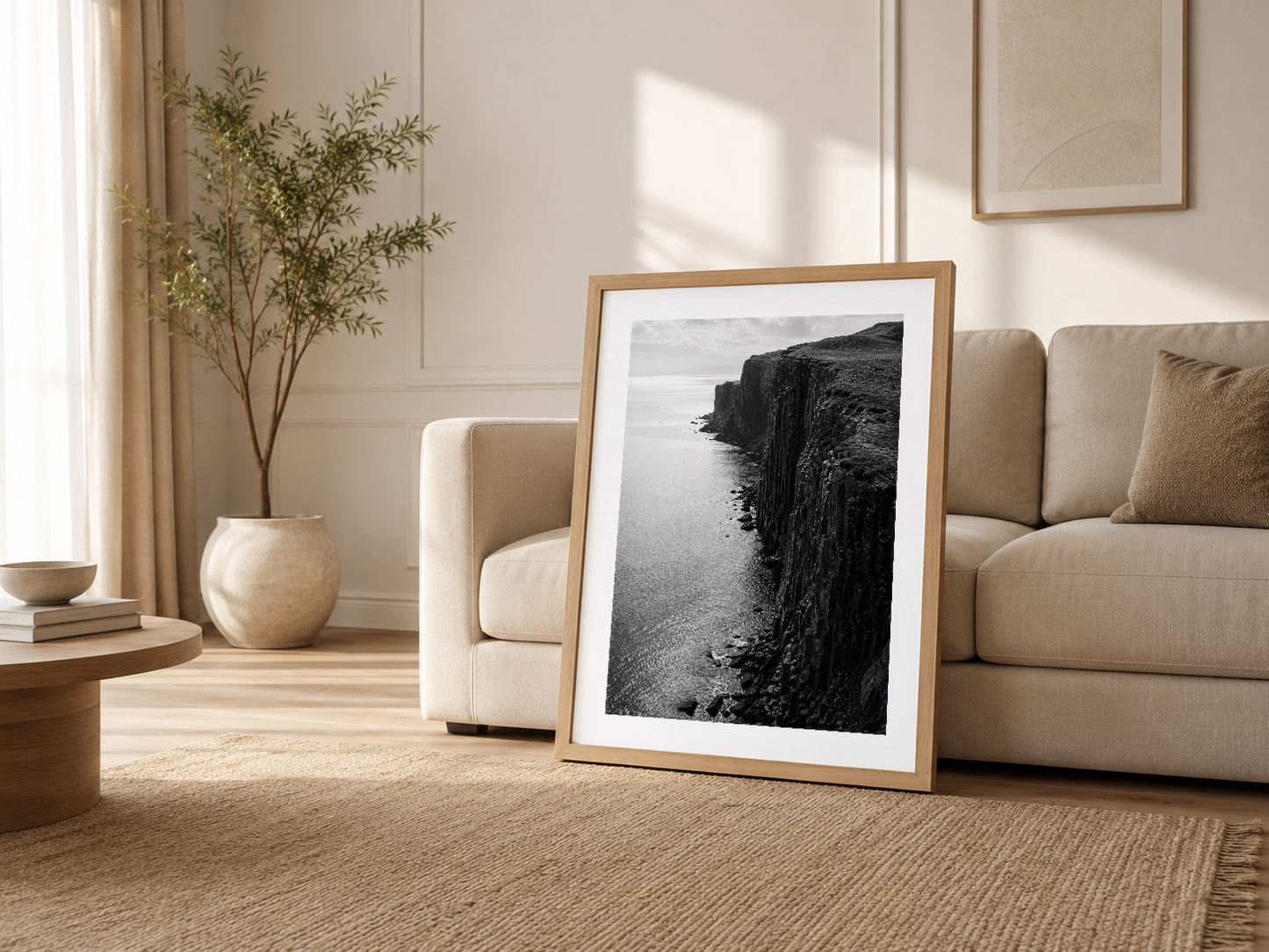 Minimalist oturma odasında, ahşap çerçevede sergilenen siyah-beyaz kıyı manzarası sanat baskısı.
