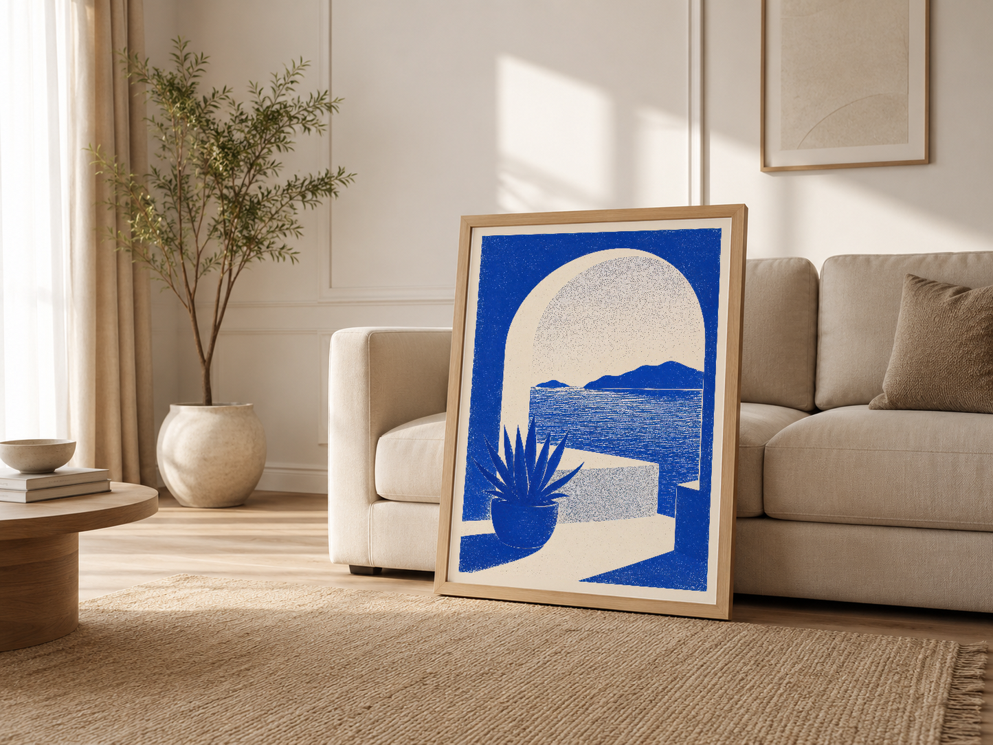 Ahşap çerçeveli mavi kıyı sanat eseri, krem rengi kanepesinin yanında duran, ışık dolu oturma odasında sergilenen poster.