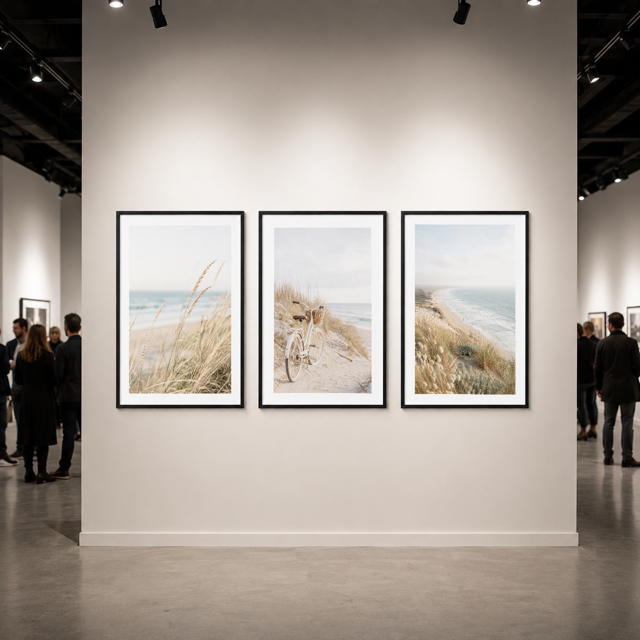 Galeride sergilenen siyah çerçeveli üç panel tablo, deniz manzarası ve bisiklet sahnesi ile ilgi çekiyor.