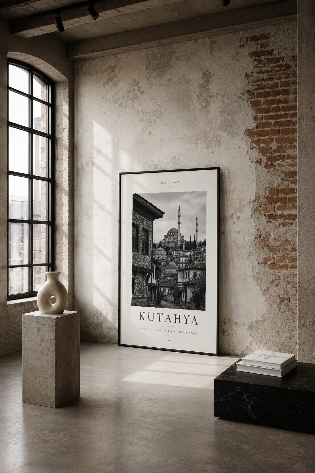 Kütahya şehrinin siyah beyaz mimarisini gösteren, endüstriyel bir mekan içinde asılı sanatsal poster.