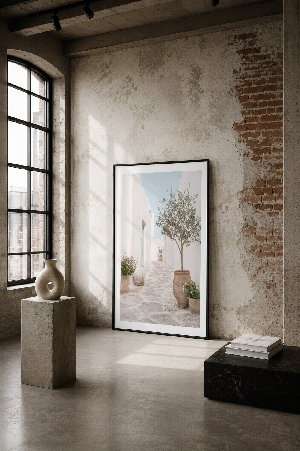 Beyaz akdeniz mimarisi ve bitkilerin serenliğini gösteren minimalist sanat tablosu, endüstriyel loft ortamında sergilenmekte.