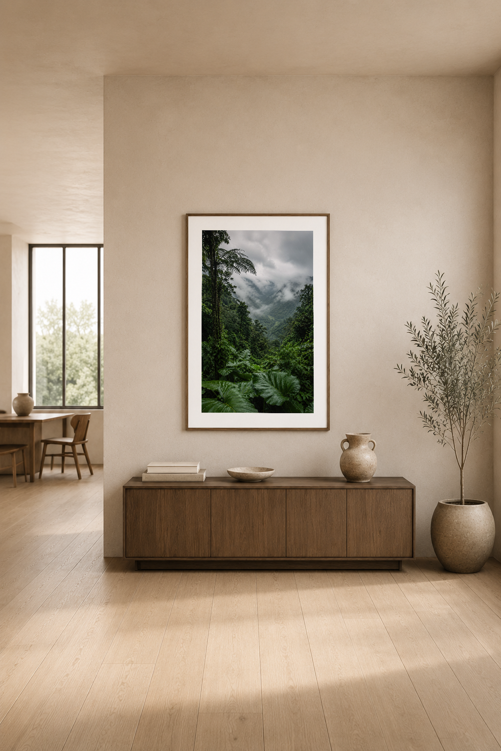 Warm minimalist oturma alanında, beyaz çerçeveli yeşil orman ve bulutlu gökyüzü posteri konsol üstünde.